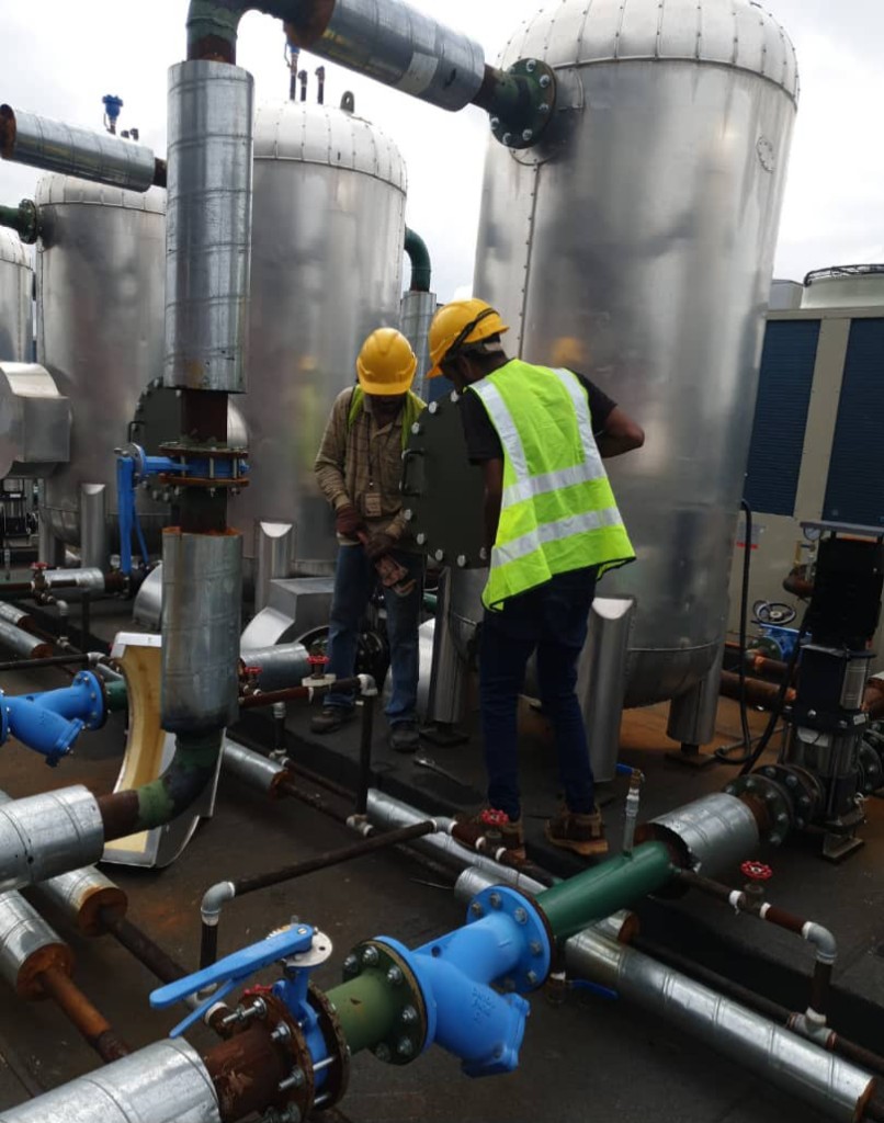 Crew coordinating industrial tanks and piping on a Malaysian project site